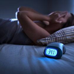 Alarm showing 3:41; woman wide awake in background