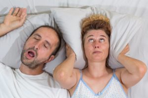 woman covering head while man snores
