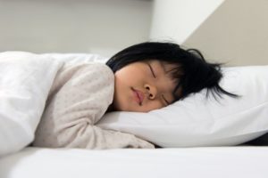 Young girl sleeping on bed with white sheets