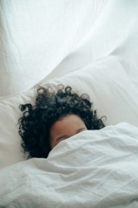 Woman in bed with blanket over her head