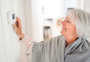 Senior woman adjusting her thermostat at home